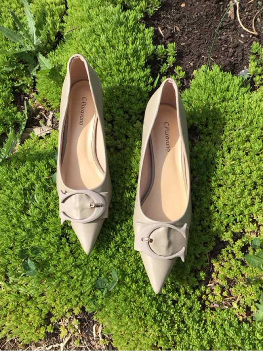 Beige pointed-toe flats with buckle detail on top, size 38, on green ground background.