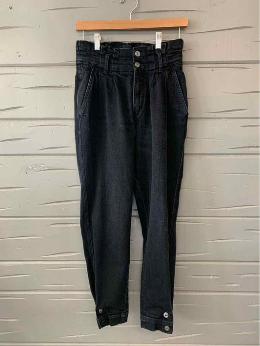 High-waisted black denim pants with button fly and ankle strap detailing on size 4 model.