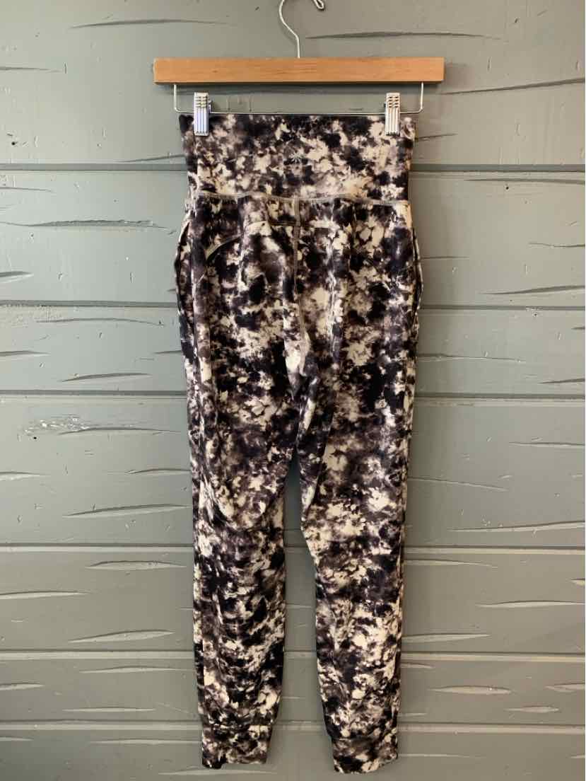 Black and white tie-dyed high-waisted leggings with a fitted silhouette hanging on a wooden hanger.