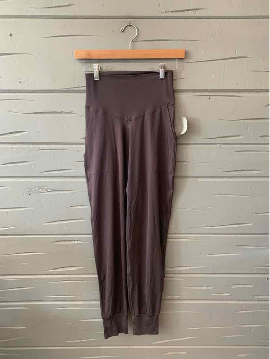 High-waist solid gray leggings with wide waistband hanging on wooden hanger against textured wall.