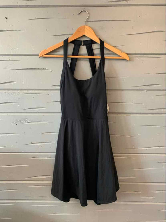 Black sleeveless dress with fitted bodice and flared skirt hanging on wooden hanger.