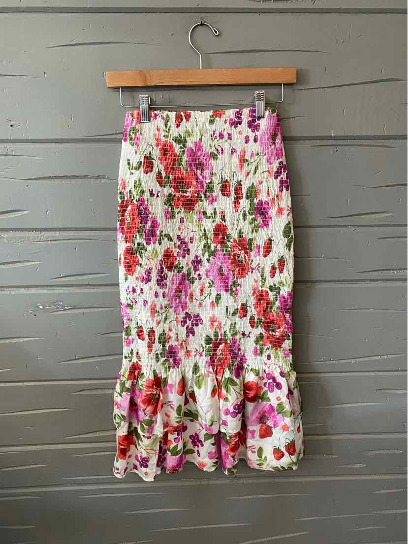 White midi skirt with pink and red floral print and flounced hem.