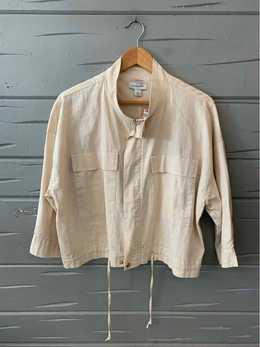 Cream-colored lightweight jacket with a stand collar, front zip, two chest pockets, and adjustable drawstrings at the hem.