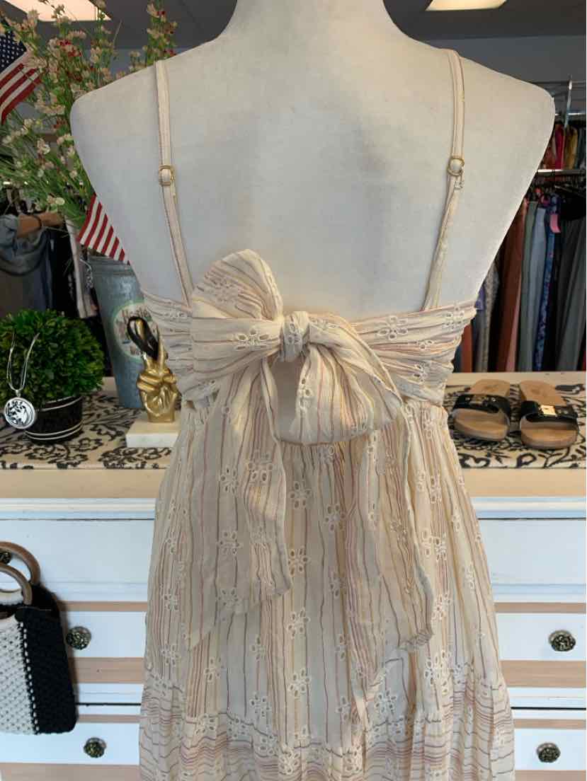 Light beige sleeveless dress with adjustable thin straps and a large bow tied at the back.