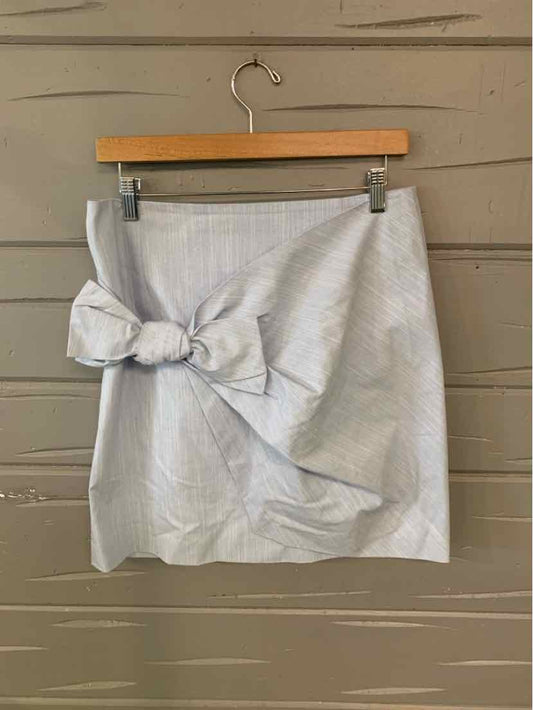 Light blue mini skirt with front knot detail and subtle texture on wooden hanger.