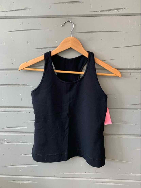 Black sleeveless tank top with a scoop neckline on wooden hanger against gray wooden background.