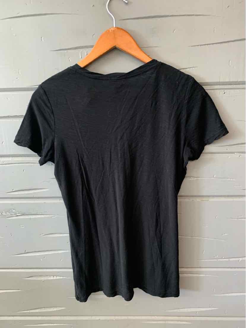 Black short-sleeve crew neck t-shirt with a slim fit, hanging on a wooden hanger against a textured beige wall.