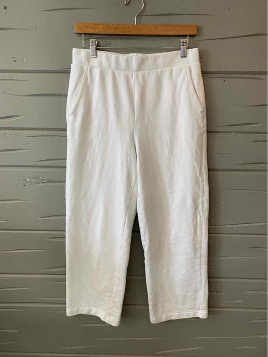 White cropped pants with a straight-leg cut and elastic waistband hanging on a wooden hanger.