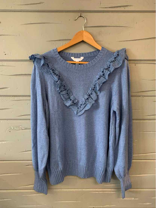 Blue long-sleeve knit sweater with ruffled V-shaped detail across chest and shoulders, ribbed cuffs and hem.