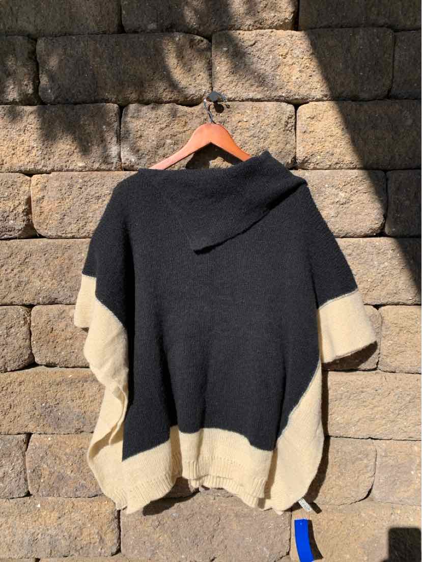 Black and cream color-block knit poncho with a draped cowl neckline and loose, short sleeves.