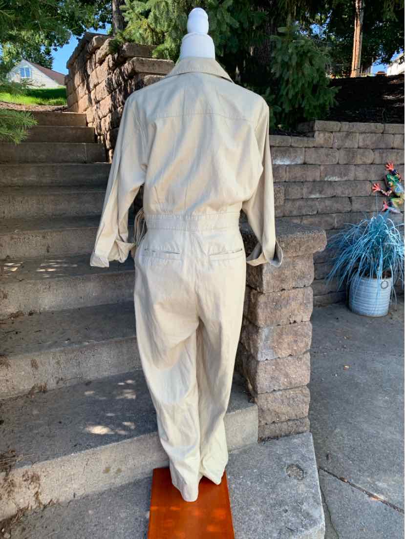 Tan long-sleeve jumpsuit with collar, cinched waist, and straight-leg pants in lightweight fabric.