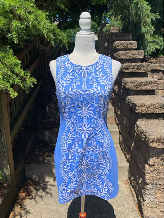 Sleeveless blue dress with white floral and leaf pattern, round neckline, knee-length, fitted silhouette.
