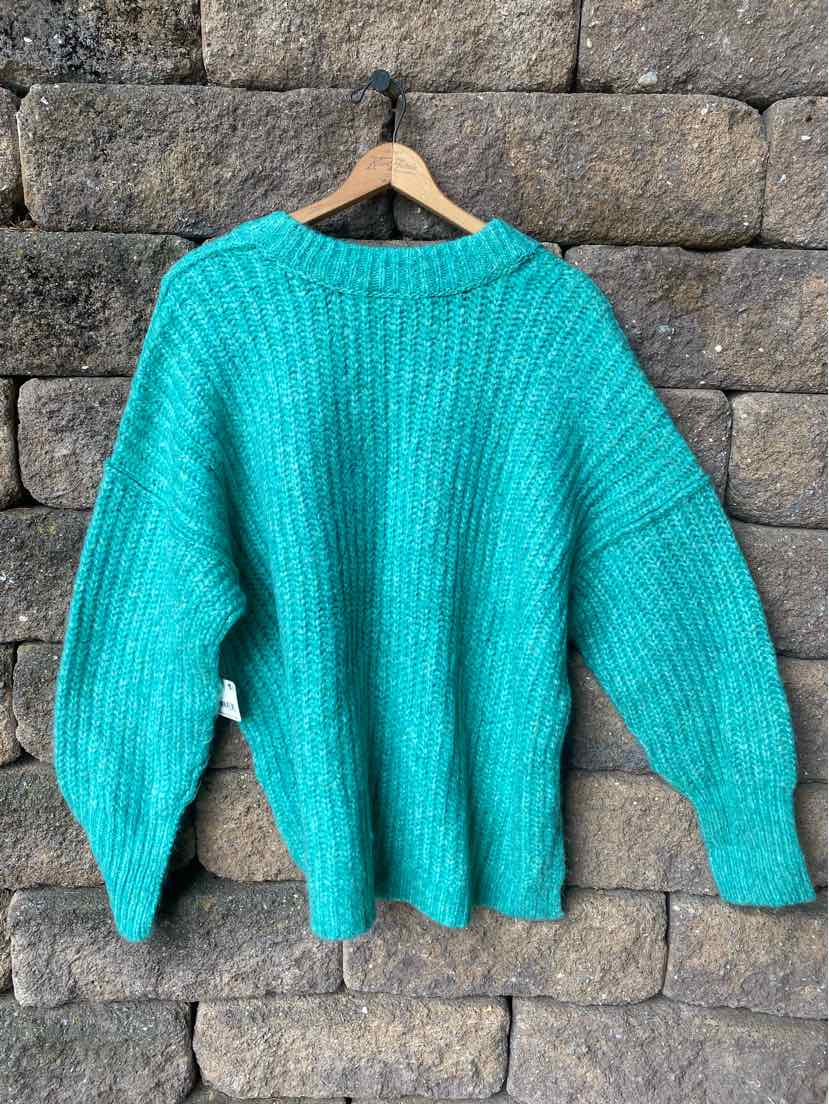 Teal chunky knit sweater with ribbed texture and long sleeves on wooden hanger.