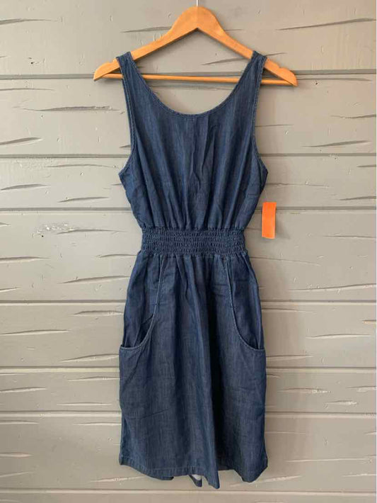 Sleeveless dark blue knee-length dress with gathered waist and front pockets on wooden hanger.