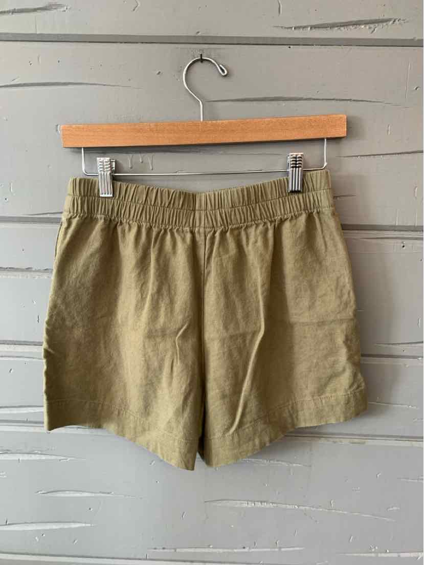 Olive green elastic waist shorts with a loose fit and lightweight fabric hanging on a wooden hanger.