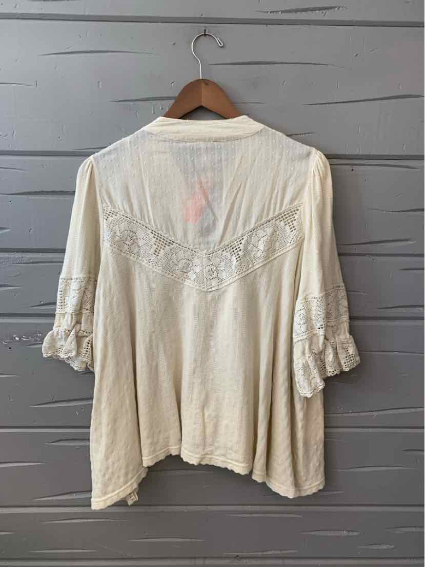 Cream-colored lightweight blouse with lace detail on back yoke and ruffled three-quarter sleeves.