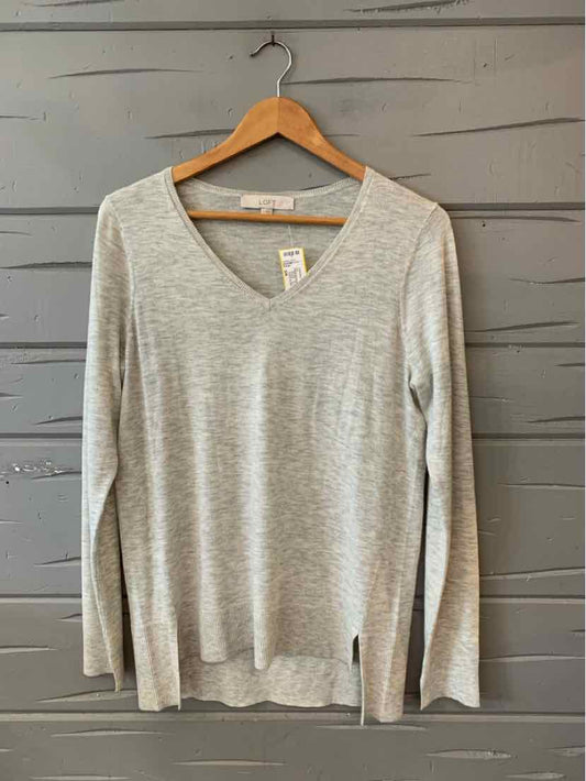 Light gray long-sleeve V-neck knit sweater with a relaxed fit on wooden hanger.