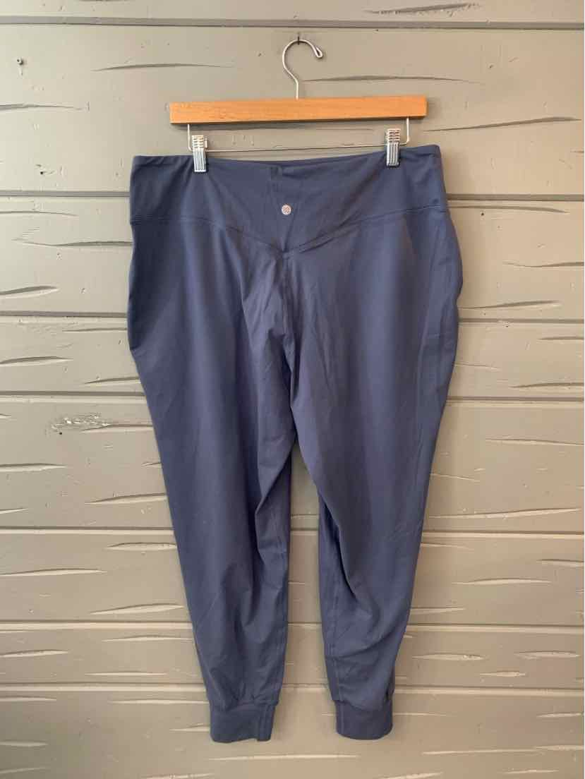 Navy blue casual pants with elastic ankle cuffs and front button closure hanging on wooden hanger.
