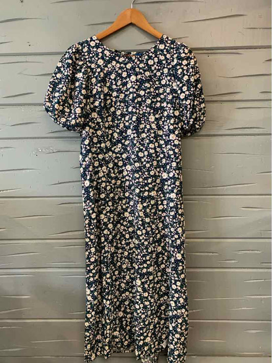 Navy blue floral dress with puff sleeves and midi length hanging on wooden hanger.