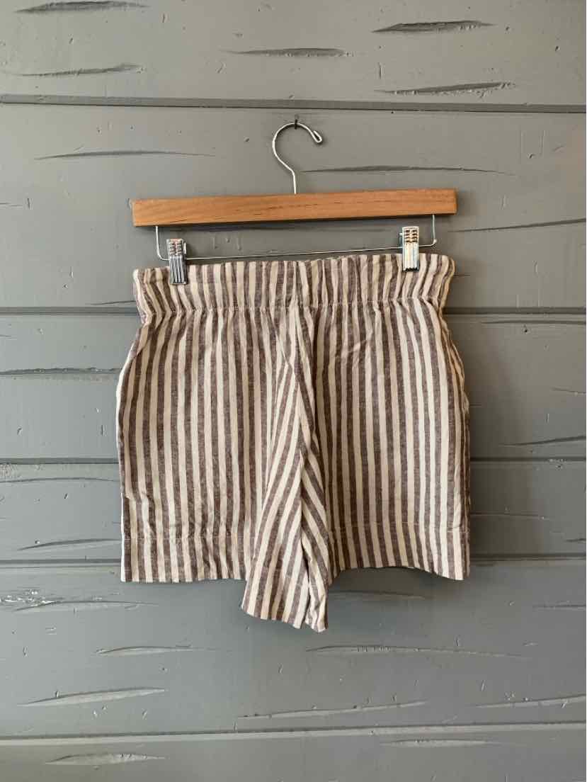 Beige and white vertical striped casual shorts with elastic waistband hanging on wooden hanger.