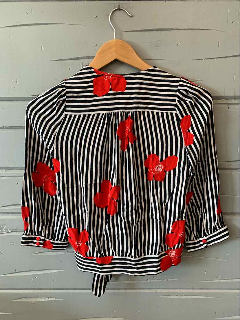 Black and white vertical striped blouse with red floral print and tie-waist detail on wooden hanger.