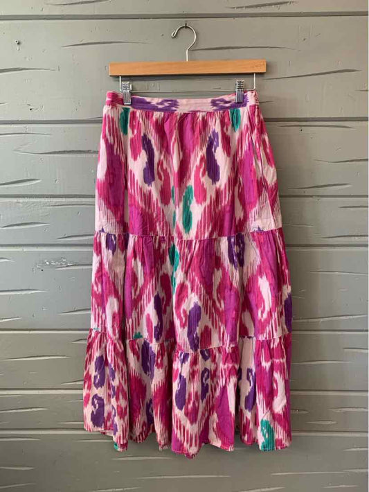 Pink midi skirt with vibrant ikat-inspired abstract patterns in purple, teal, and white, featuring a tiered, flowy design.