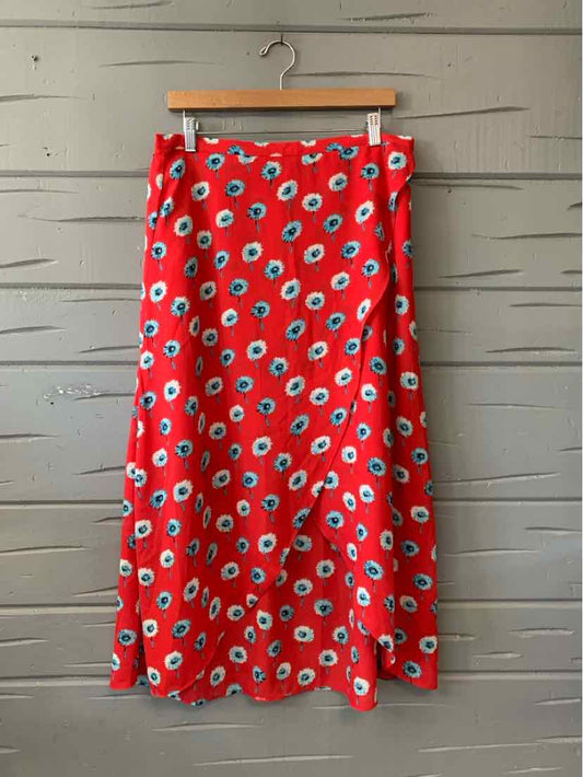 Red midi skirt with blue and white floral print, button details at the waist, hanging on wooden hanger.