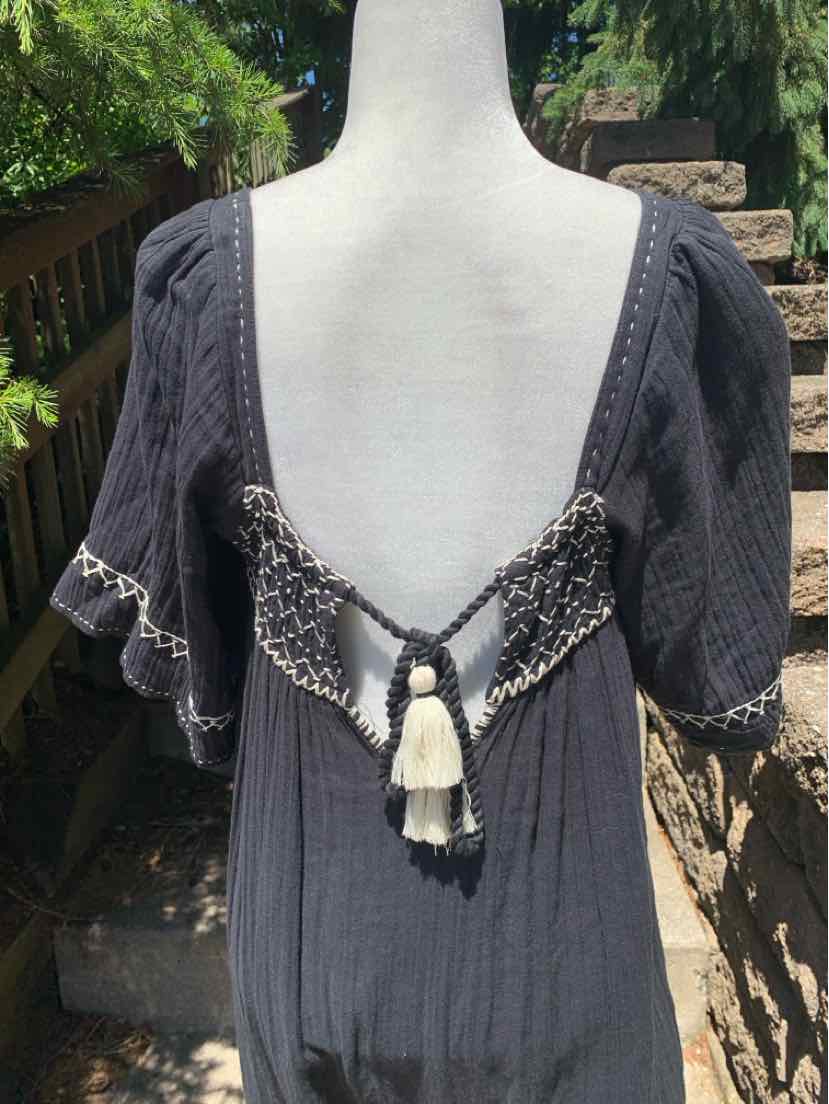 Black dress with deep square neckline, short puffed sleeves, and decorative crochet back tie with tassels.