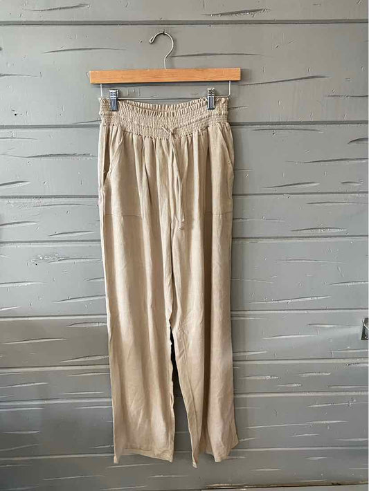 Tan high-waisted wide-leg pants with elastic waistband hanging on wooden hanger.