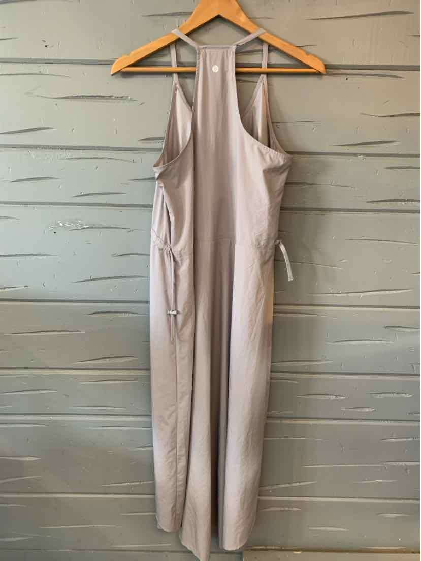 Beige sleeveless apron with side ties and a round neckline hanging on a wooden hanger.