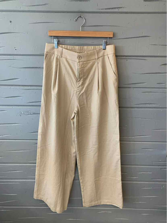 Tan wide-leg pants with elastic waistband and side pockets hanging on wooden hanger.