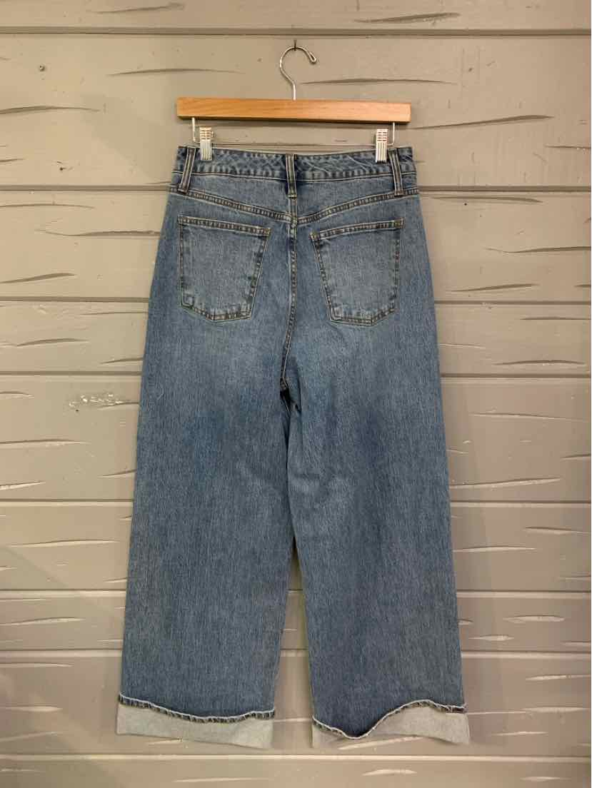 High-waisted blue denim jeans with a relaxed wide-leg fit and rolled hems, featuring two back pockets.