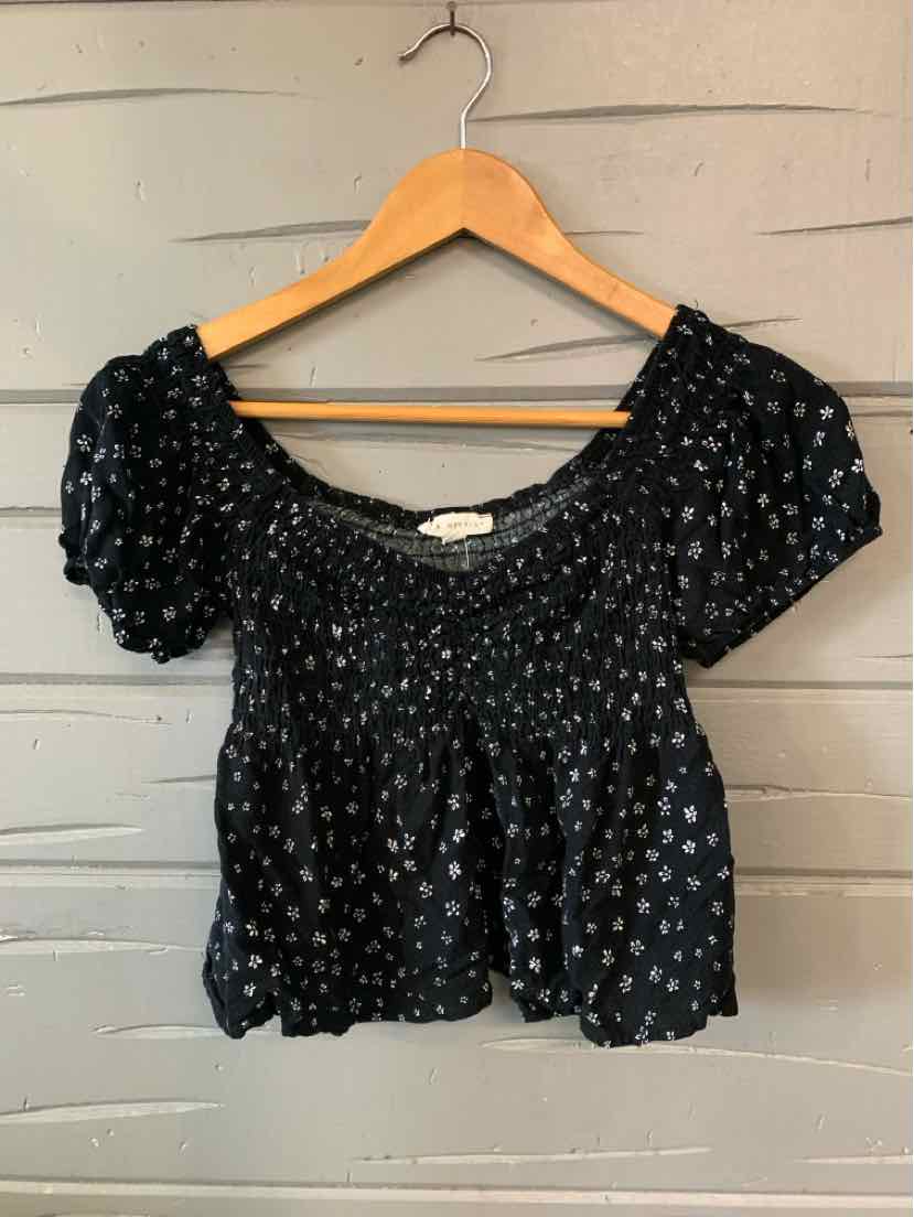 Black cropped blouse with white floral print, smocked bodice, and puff sleeves.