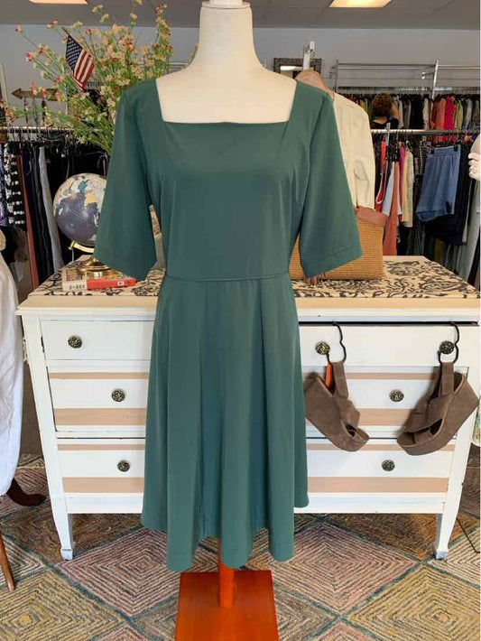 Dark green dress with square neckline and elbow-length sleeves on mannequin.