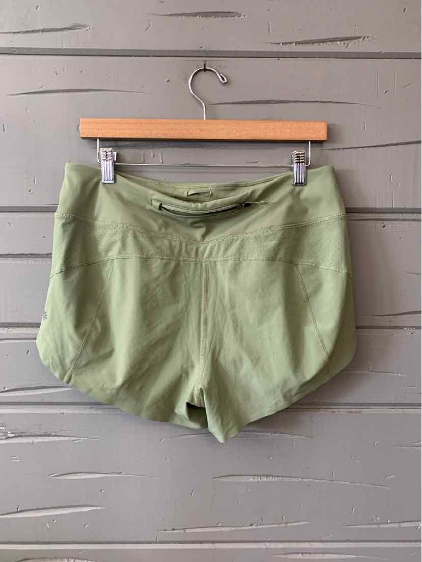 Light green athletic shorts with curved hem and front seam detail, hanging on wooden hanger.