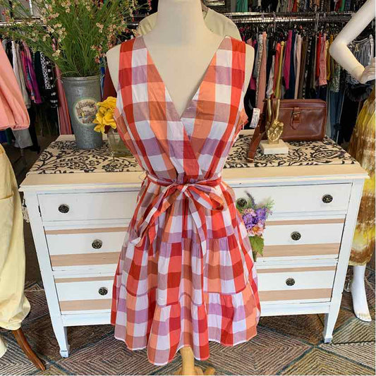 Sleeveless orange and white plaid dress with V-neck and waist tie on mannequin.