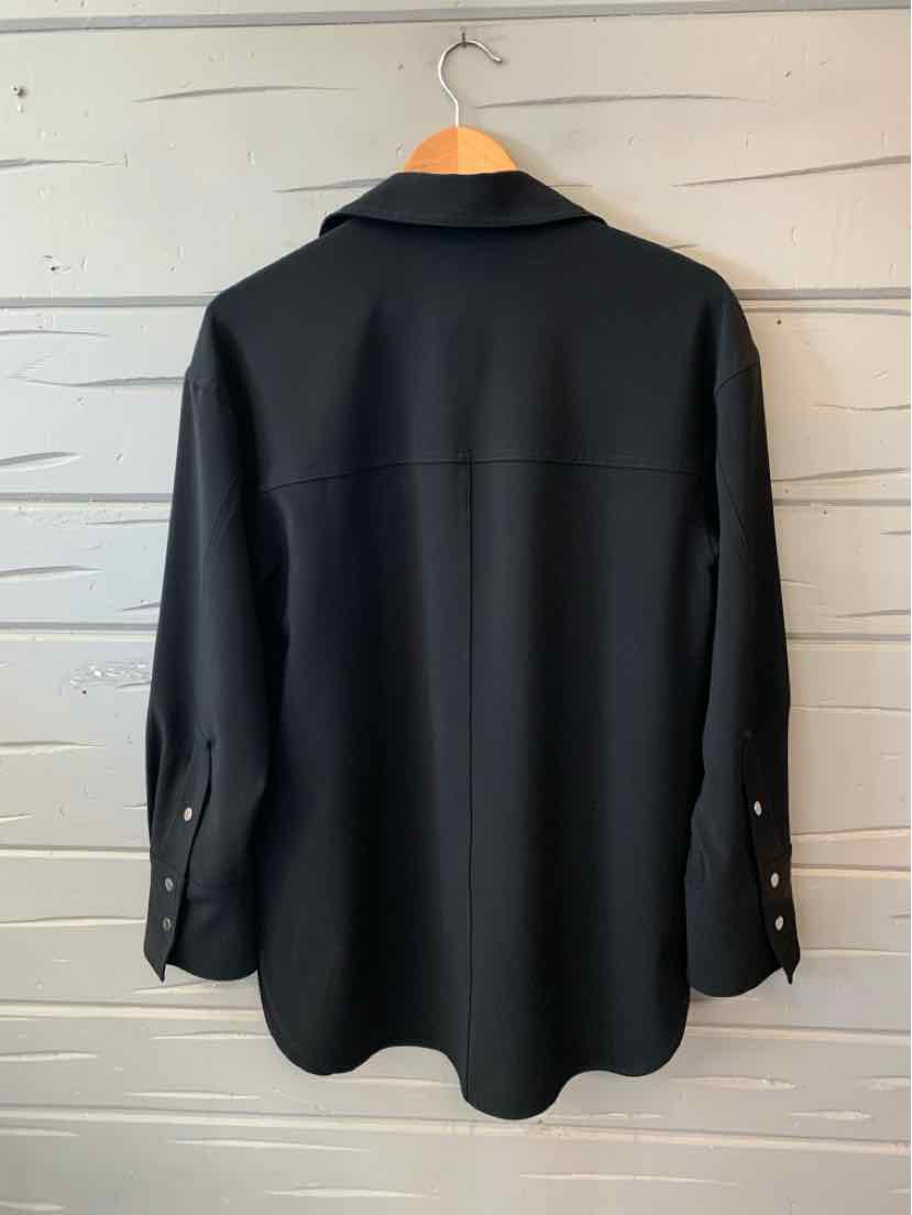 Black long-sleeve button-up jacket with collar and buttoned cuffs, relaxed fit, hanging on wooden hanger.