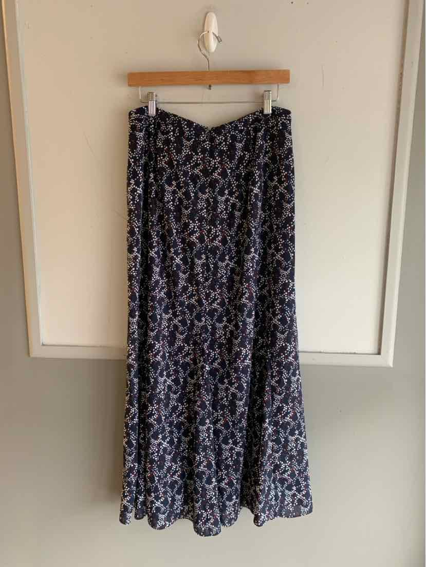 Navy blue maxi skirt with white polka dots and flowy fabric hanging on wooden hanger.