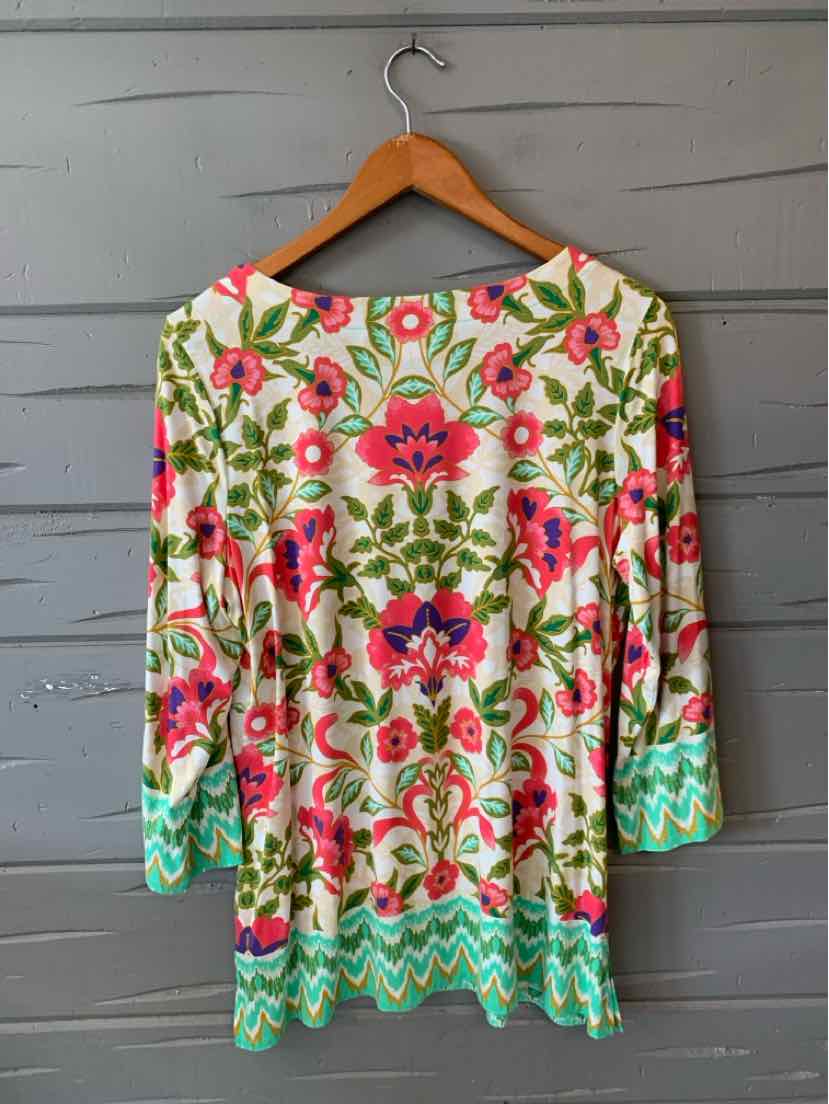 Long-sleeve tunic with bright pink and green floral print on cream background and turquoise zigzag border.