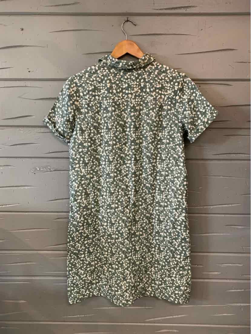 Green-gray short-sleeve dress with a dense white floral print and high neckline, hanging on a wooden hanger.