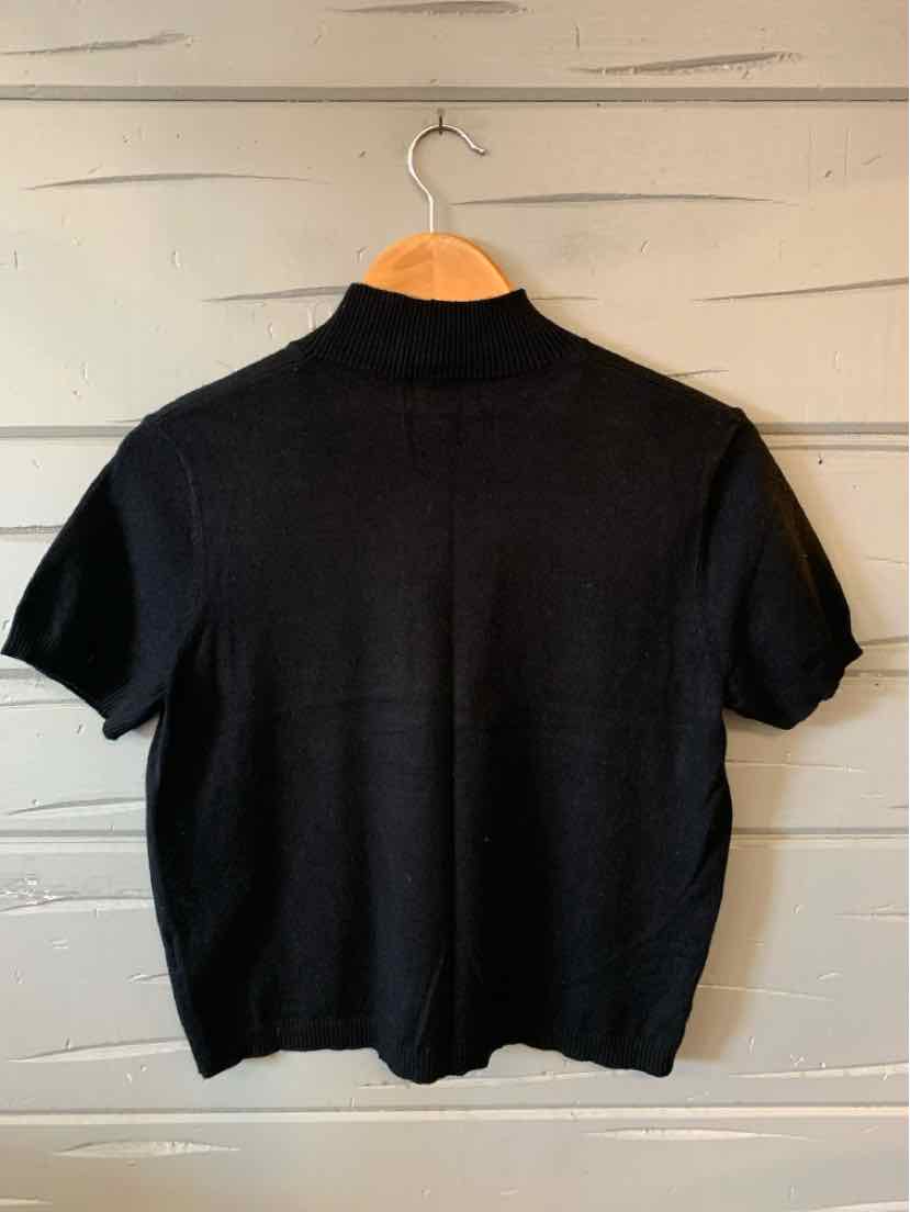 Black short-sleeve knit top with mock neck and relaxed fit hanging on wooden hanger.
