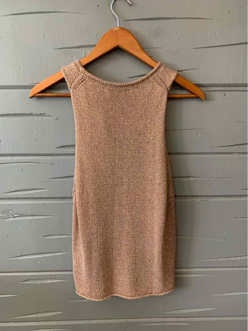 Sleeveless tan knit top with high neckline on wooden hanger against gray wooden wall.