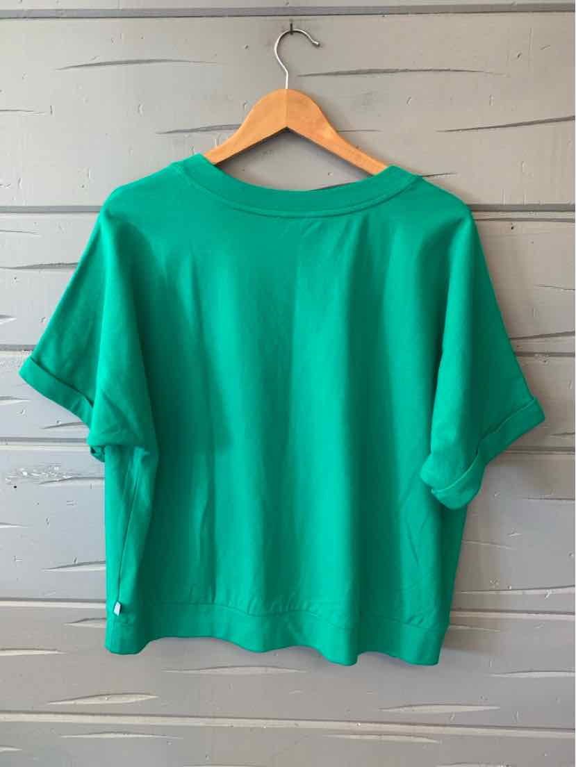 Green short-sleeve blouse with loose fit and cuffed sleeves on wooden hanger.