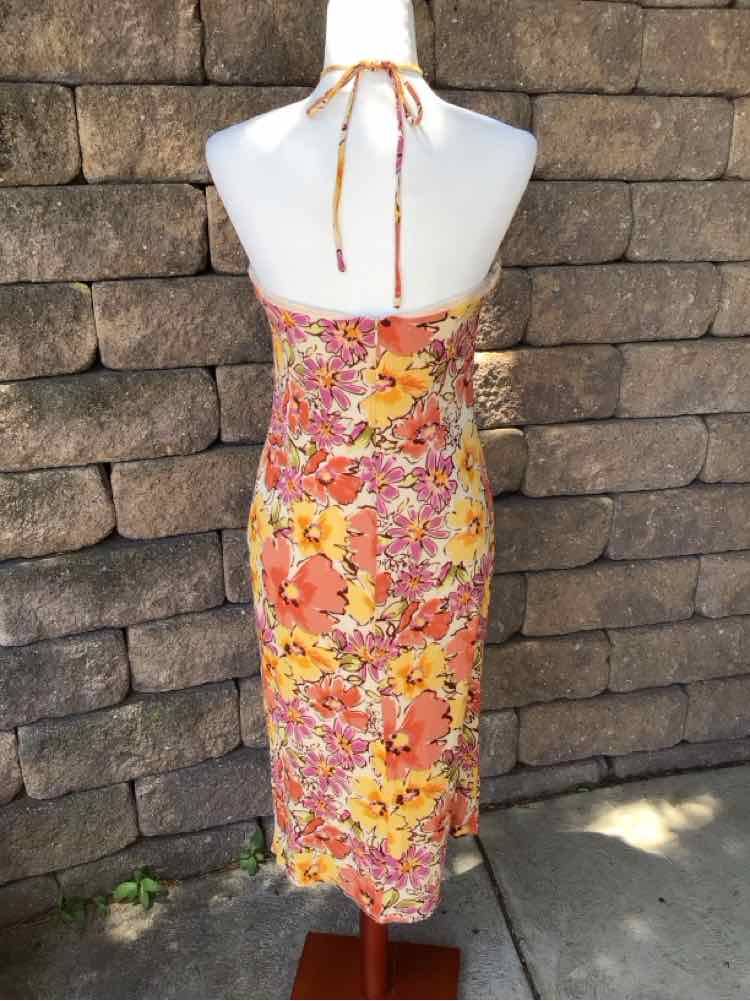 Sleeveless floral midi dress with halter neck tie, featuring orange, pink, and yellow flowers on fitted silhouette.