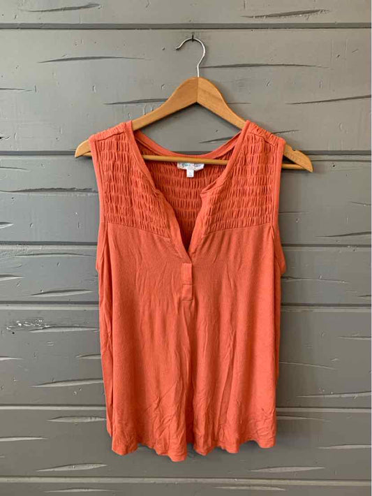 Orange sleeveless blouse with lace yoke and V-neck on wooden hanger.