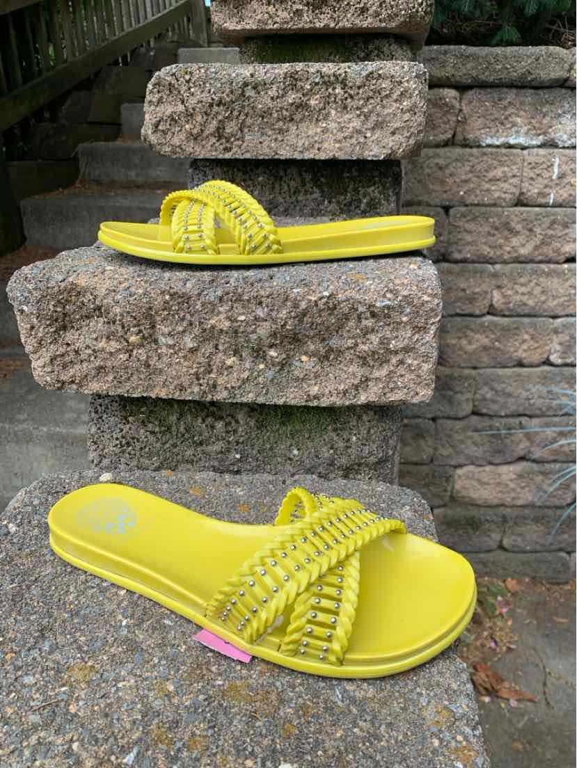 Bright yellow flat slide sandal with woven strap and textured sole.
