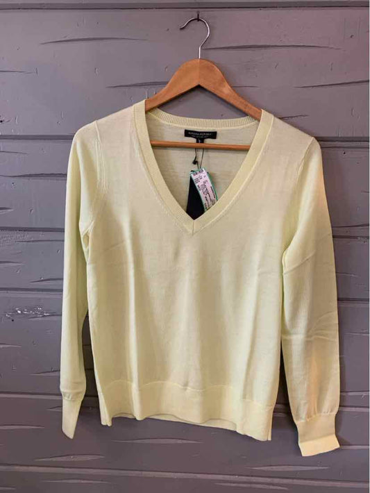 Light yellow V-neck long-sleeve sweater in medium size hanging on wooden hanger.