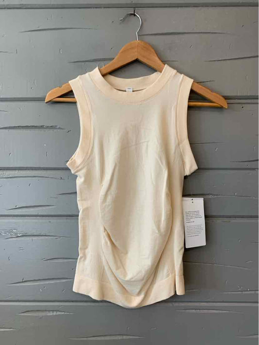 Cream-colored sleeveless athletic tank with slight ruching detail and round neckline, size XS.