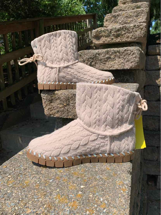 Beige ankle boots with cable knit texture, flat rubber sole, and drawstring detail at heel.