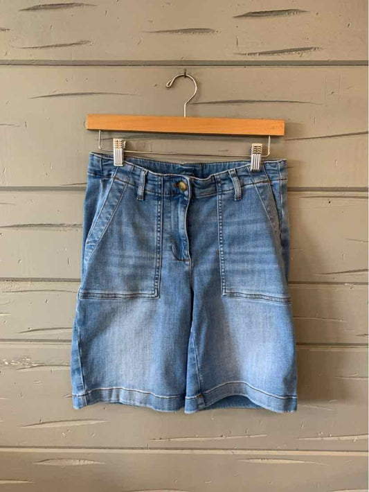 Light blue washed denim shorts with a high waist, front button, and pockets hanging on wooden hanger.